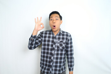 Fototapeta premium funny asian man showing okay symbol using hand with surprised and shocked expression isolated on white
