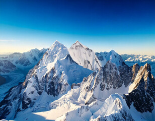 Obraz premium A breathtaking aerial view of snow-capped mountain peaks stretching towards a clear blue sky. The majestic landscape evokes a sense of awe and wonder