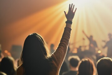 person raising hand at a concert with bright lights