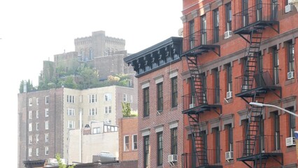 Fototapeta premium New York City classic building architecture, Manhattan, USA. Urban residential house exterior. Real estate property in United States. Typical red brick facade. Fire escape, emergency ladder exit.