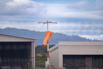 Capture the essence of aviation safety with this image of a vibrant orange windsock against a...
