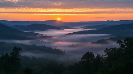 Obraz premium A serene sunrise over a misty mountain range with warm light illuminating the peaks and deep shadows in the valleys