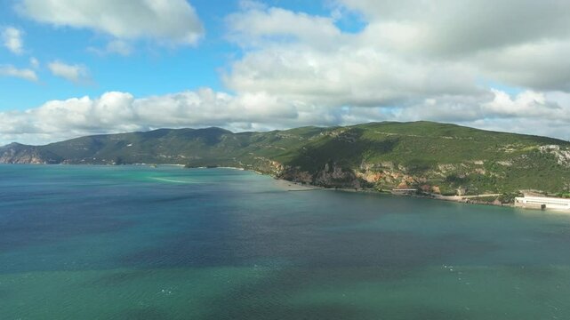 Aerial establishing shot of Arrabida natural park scenery by turquoise colored water, Setubal