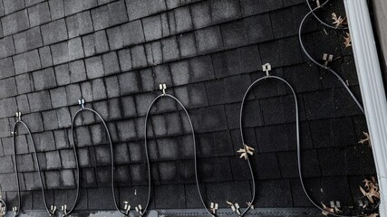 full frame perspective of a deicing system installed on asphalt shingle roof used to melt paths...