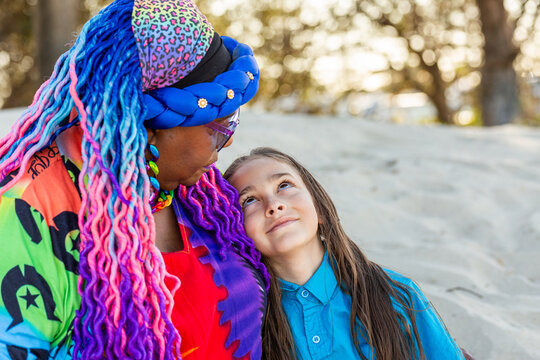Torres Strait Islander nine year old boy with long hair sitting beside grandmother on beach