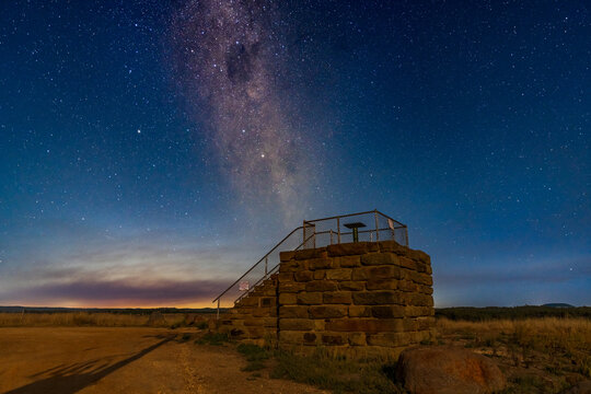 Looking up at the milky way galaxy above a stone lookout platform against the night sky
