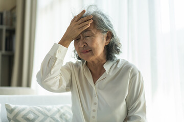 Sick unhappy senior elderly woman touching head serious depressed feeling headache thinking of...