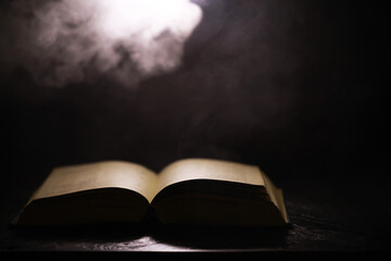 Mysterious Open Book with Dramatic Lighting and Smoky Background in Dark Setting