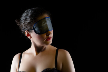 One Winsome Caucasian Brunette Woman Wearing Black Sleep Mask Against Black Background