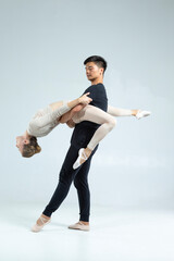 Professional International Sportive Couple of Asian Man and Caucasian Woman Performing As Ballet Dancers Over Grey in Studio During Suppots in Classical Dance © danmorgan12