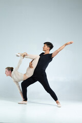 Professional International Sportive Couple of Asian Man and Caucasian Woman Performing As Ballet Dancers Over Grey in Studio During Suppots in Classical Dance © danmorgan12