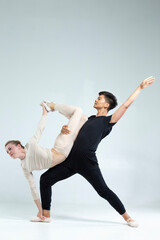 Professional International Sportive Couple of Asian Man and Caucasian Woman Performing As Ballet Dancers Over Grey in Studio During Suppots in Classical Dance Choreography. © danmorgan12
