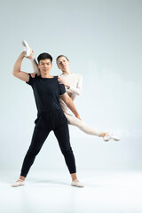 Professional Sportive Couple of Asian Man and Caucasian Woman Performing As Ballet Dancers Over Grey in Studio During Suppots in Classical Dance © danmorgan12