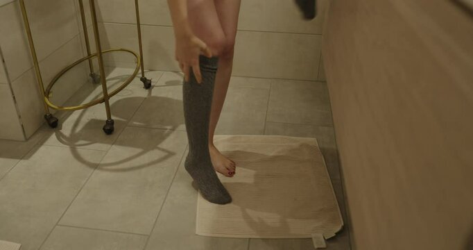 a woman takes off her socks in the bathroom