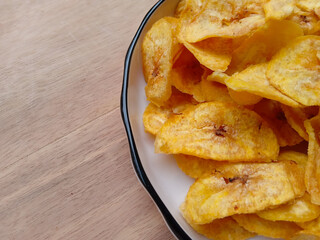 banana chips on plate on wooden bakground. Homemade dried banana chips. popular traditional...