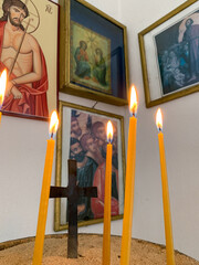 Three lit candles are placed in front of religious icons, creating a serene and spiritual atmosphere within the church.