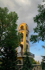 The Bell Tower in Haskovo, Bulgaria, stands tall with its distinct brick design, arches and ornate dome with Christian cross on top.