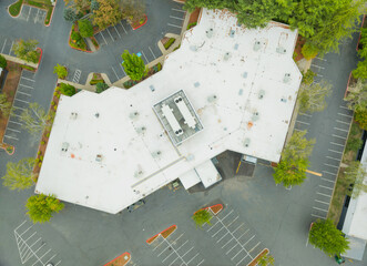 A white building with a roof and a parking lot below © Anton