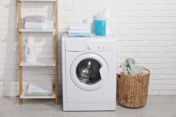 Laundry detergents and stacked clean towels on washing machine in bathroom