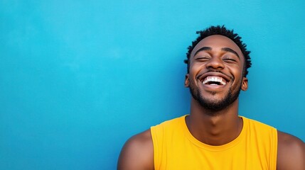 Obraz premium Joyful Black Man Laughing Heartily Against Vibrant Blue Background