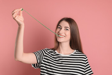 Young woman eating tasty gummy candy on pink background