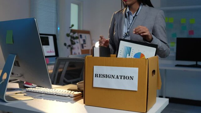 Businesswoman holding resignation letter in box with personal belongings at desk in office for changing job. Concept of resignation or changing job for future.