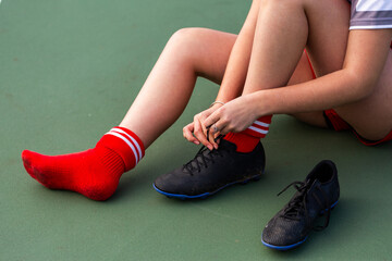 Teen football player putting on sports shoes tying laces