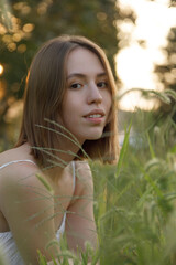 Naklejka premium This is a captivating portrait of a young woman, beautifully captured in a sunlit field