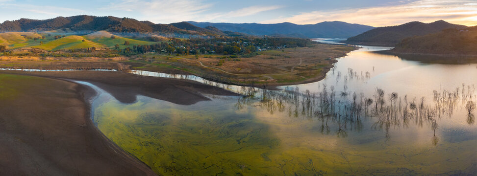 Aerial panorama of a drying lake full of dead tress below a mountain range at twilight