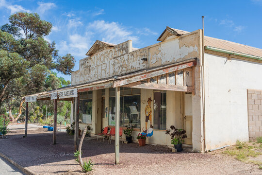 An old run down electrical store with seta under a wide veranda