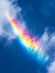 Fototapeta premium A vibrant rainbow streak illuminates the clouds against a deep blue sky.