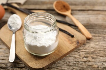 Baking powder in jar on wooden table, closeup