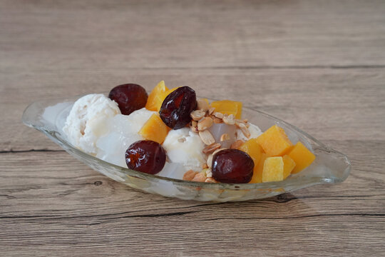 top view Coconut milk ice cream topped with coconut jelly, nuts, dried puttha, and welded in a glass bowl, on wooden floor background, object, food, dessert, sweet, copy space