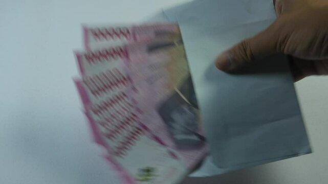 "Indonesian rupiah banknotes inside a white envelope isolated on a clean background. Concept of money savings, financial planning, payment, and personal finance with realistic details
