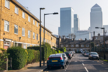 Council houses contrasted against the towering skyscrapers of Canary Wharf in London, UK