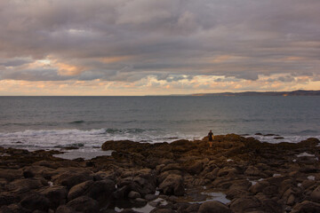 Waves crashing into coastal rocks at sunset. Dramatic sea coast background. Raglan, New Zealand