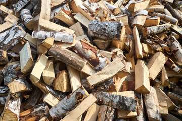 Stack of birch firewood with hand chopping block. Chopped firewood for winter. Lot of firewood - harvesting wood for heating the house. Horizontal photo. Chopped firewood background and texture.