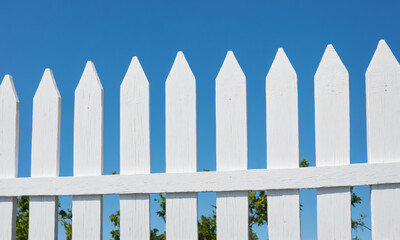 White picket fence against a clear blue sky