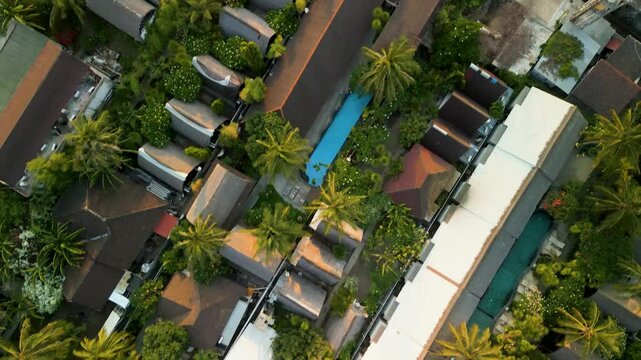 Aerial view of luxurious villas and palm trees surrounding a serene pool in a tropical paradise, Gilli Trawangan, Indonesia.