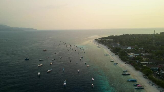 Aerial view of Gilli Trawangan with boats on the tranquil sea at sunset, Bali, Indonesia.