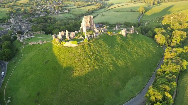 Aerial view of historic Corfe Castle ruins surrounded by picturesque countryside and greenery, Dorset, United Kingdom.