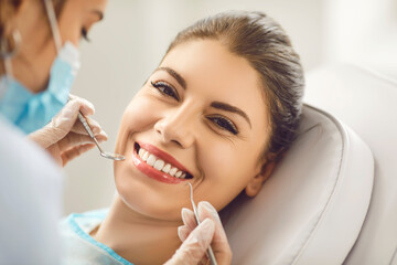 Young beautiful woman smiling at a dentist appointment, face close-up. The doctor holds dental...