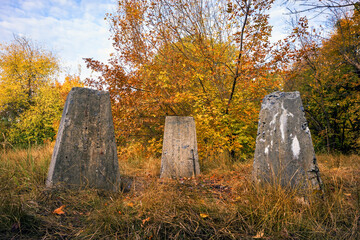 Concrete truncated pyramids stand in the forest. Strange small reinforced concrete blocks or pedestal on the grass in the garden
