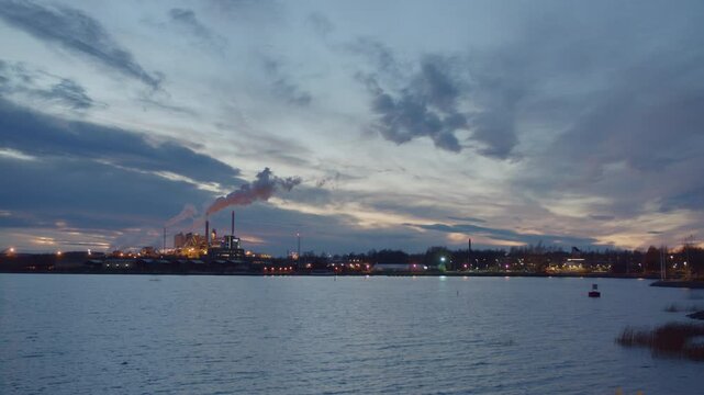 Beautiful View of Clouds on Gradient Sky, Horizon and Body of Water at Sunset, 4K Shot of Industrial Factory Producing Smoke and Pollution in Pite&aring;, Sweden, Calm Evening
