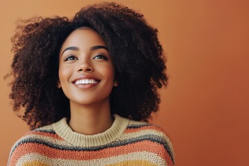 A woman with curly hair is smiling and wearing a striped sweater