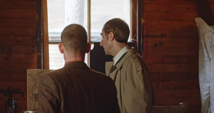 World War 2 era concept - A civilian resistance fighter walks up to a spy and they deliberate in front of a map