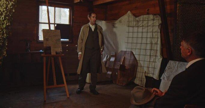 Word War 2 era concept - a spy dressed in a classic trench coat walks into a room and gives a briefing