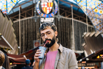 Stylish man drinking smoothie at mercat de sant josep de la boqueria in barcelona