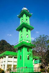 The towering green mosque minaret during the day