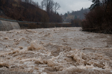 Turbulent River Overflowing Its Banks Amidst Overcast Skies